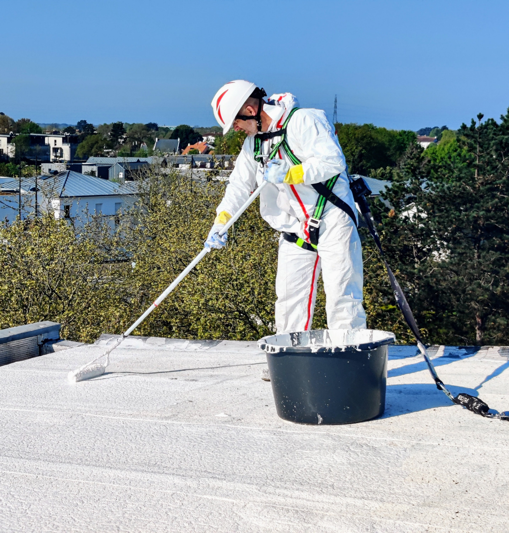 Application au rouleau de la peinture Cool Roof par un couvreur